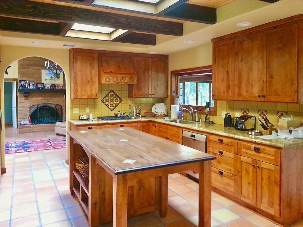 A kitchen with wooden cabinets and a large island in the middle