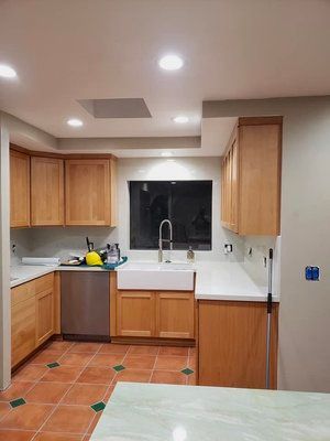 A kitchen with wooden cabinets , stainless steel appliances , a sink and a window.