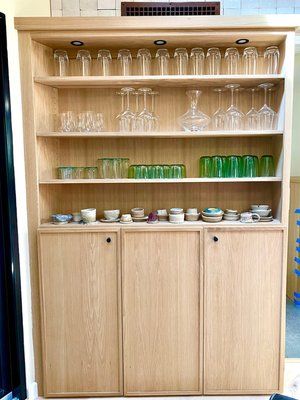 A wooden cabinet filled with wine glasses and cups.
