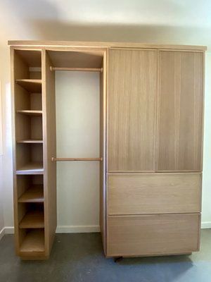 A wooden wardrobe with shelves and drawers in a bedroom.