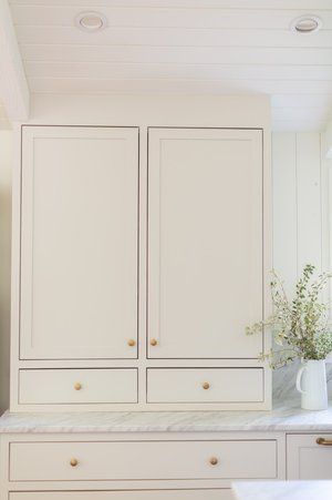 A kitchen with white cabinets and drawers and a marble counter top.