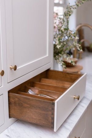 A kitchen counter with a wooden drawer filled with utensils.