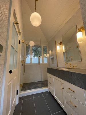 A bathroom with a sink , mirror and shower.