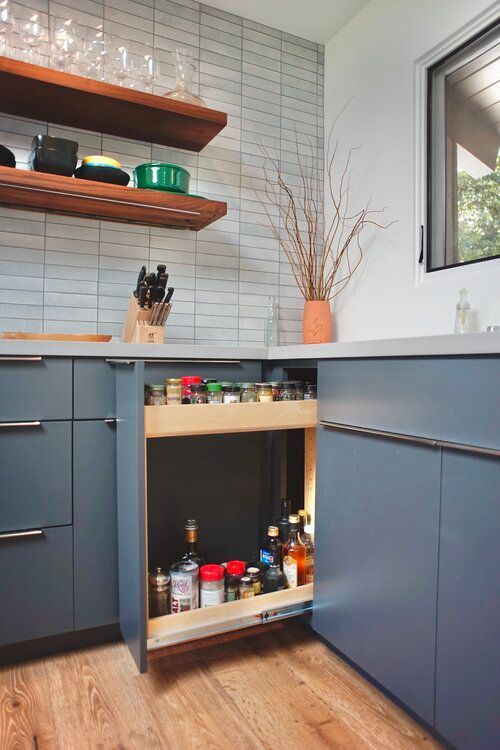 A kitchen with a pull out spice rack and a window.