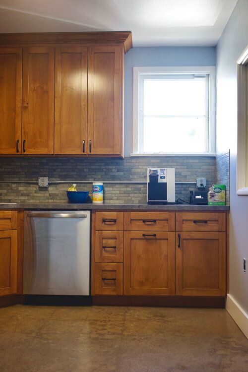 A kitchen with wooden cabinets and a stainless steel dishwasher