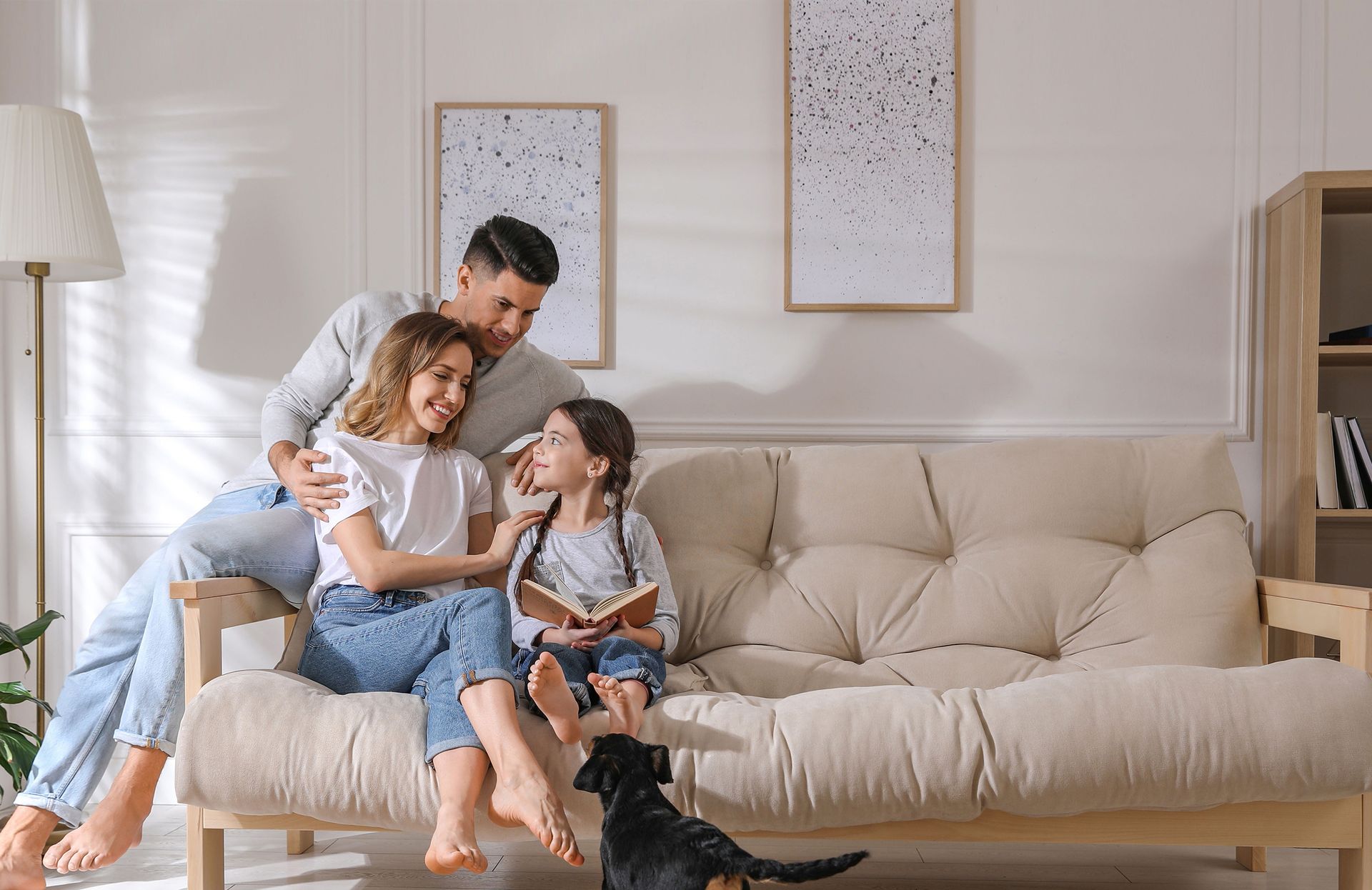 Hand holding remote, pointing it at a wall-mounted air conditioner in a room with a window and curtains.