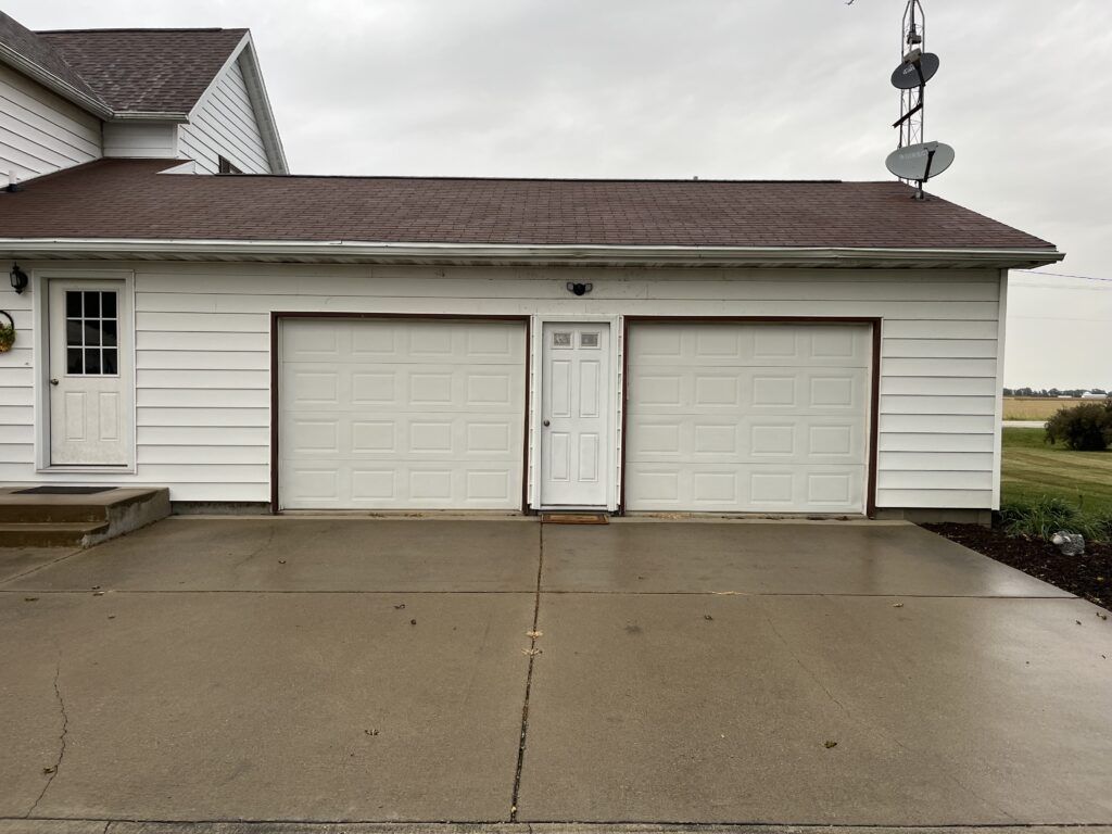 a white house with two garage doors and a satellite dish on the roof