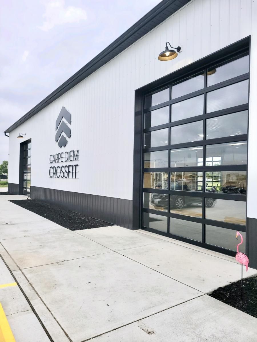 a white building with a black garage door and a flamingo in front of it