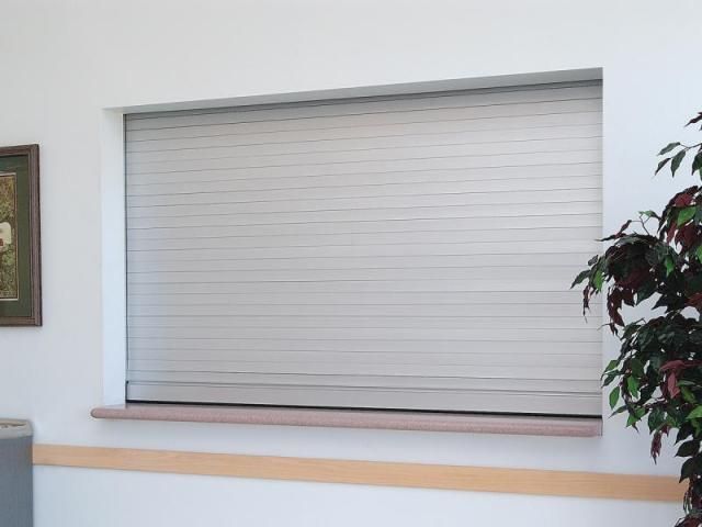 a window with a shutter on it and a picture on the wall behind it