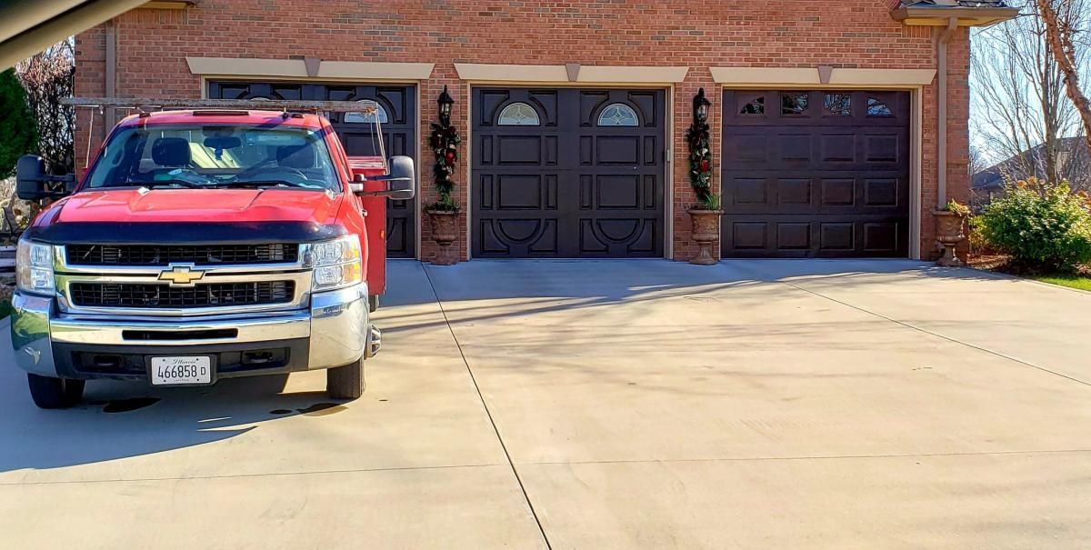 a red truck is parked in a driveway in front of a brick house