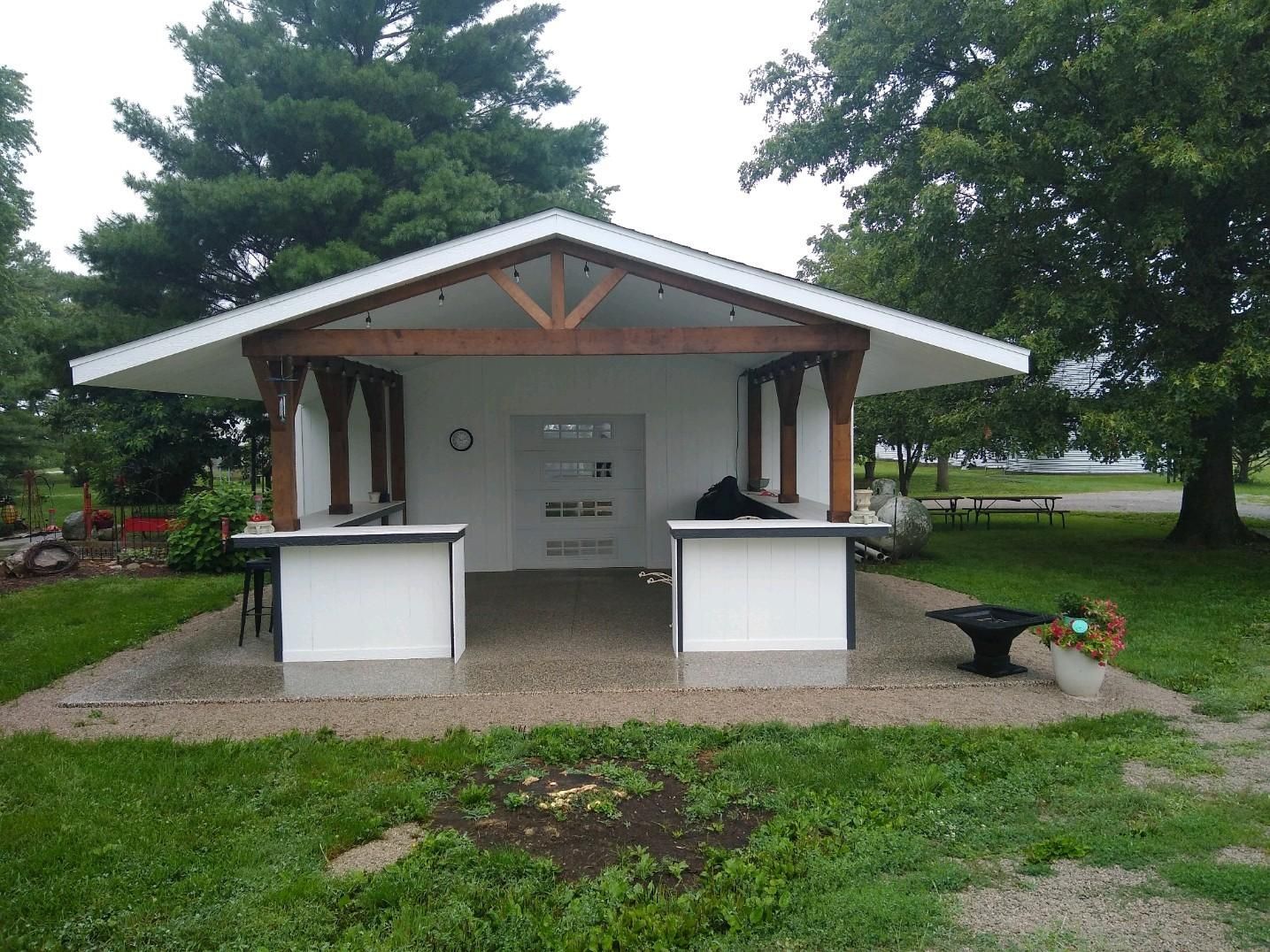 a white building with a wooden roof and two tables in front of it
