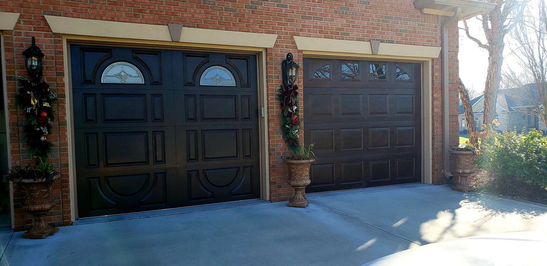 a brick house with two garage doors decorated for Christmas