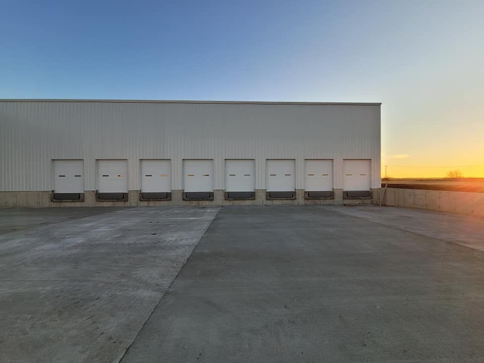 a warehouse with a lot of loading doors and a sunset in the background