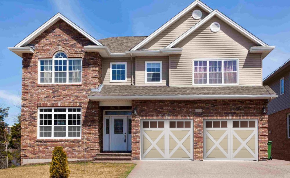 a large brick house with two garage doors and many windows