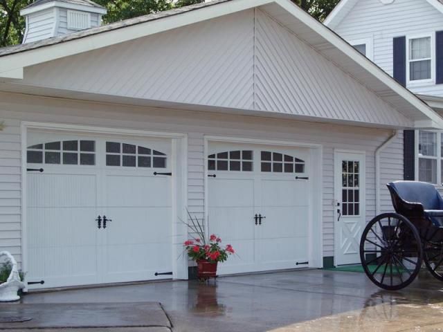 a horse drawn carriage is parked in front of a white garage