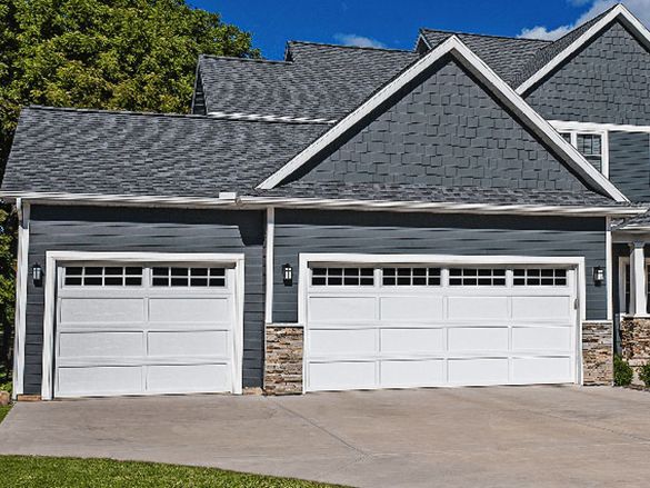 a large house with three white garage doors and a gray roof