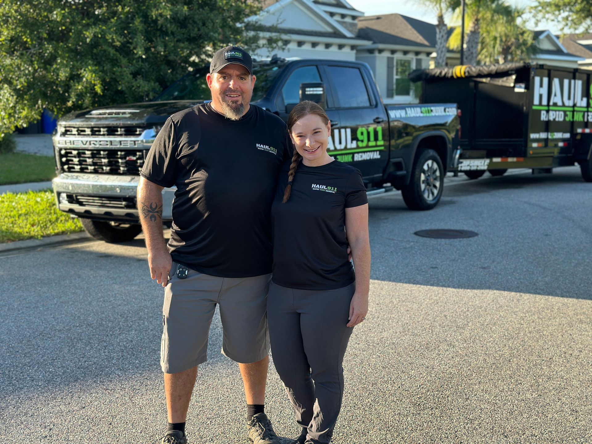 Man and woman smiling in front of a black pickup truck with a