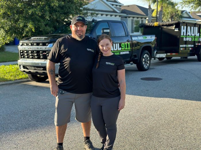 Man and woman smiling in front of a black pickup truck with a 