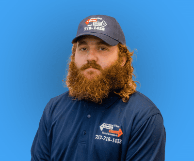 Bearded man in a navy work shirt and cap against a blue background