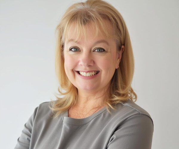 Smiling blonde woman in a gray top against a light background
