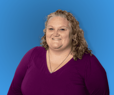 Smiling person in a purple top against a blue background