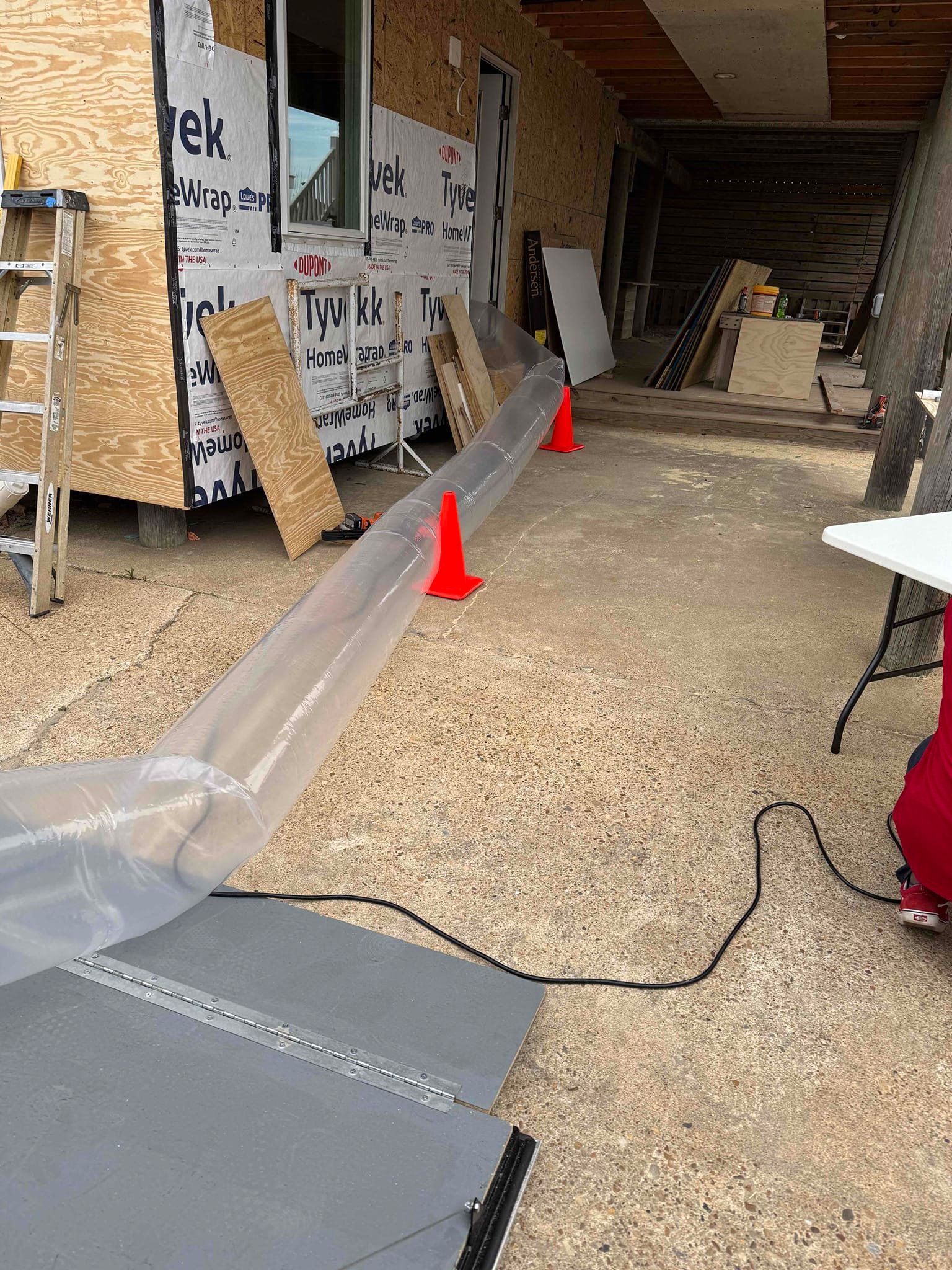 Transparent tube laid across a workshop floor with red arrows pointing to it.
