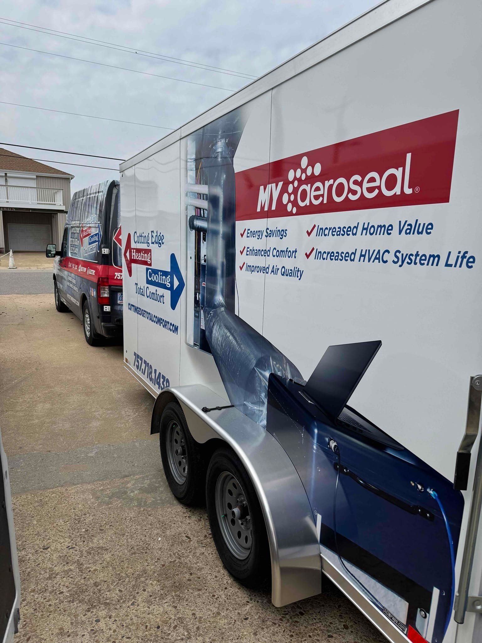 Maroon AeroSeal service trailer with blue graphics parked on a street beside houses.
