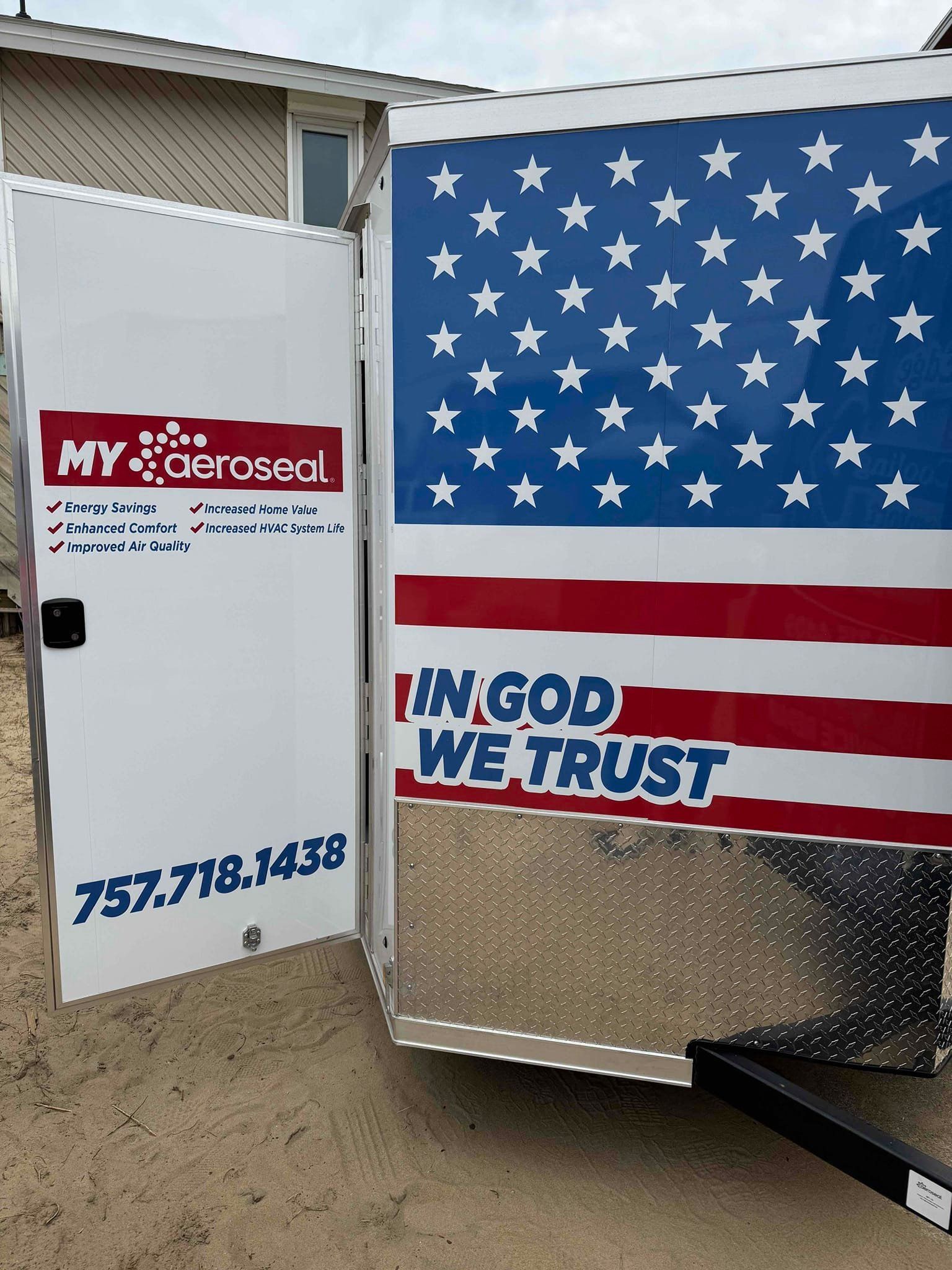 White door with My T**tcherson logo and phone number next to a trailer with a U.S. flag and “IN GOD WE TRUST” text