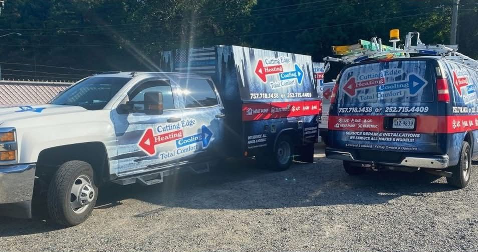 White truck and two wrapped vans with red-arrow branding parked on gravel in bright sunlight.