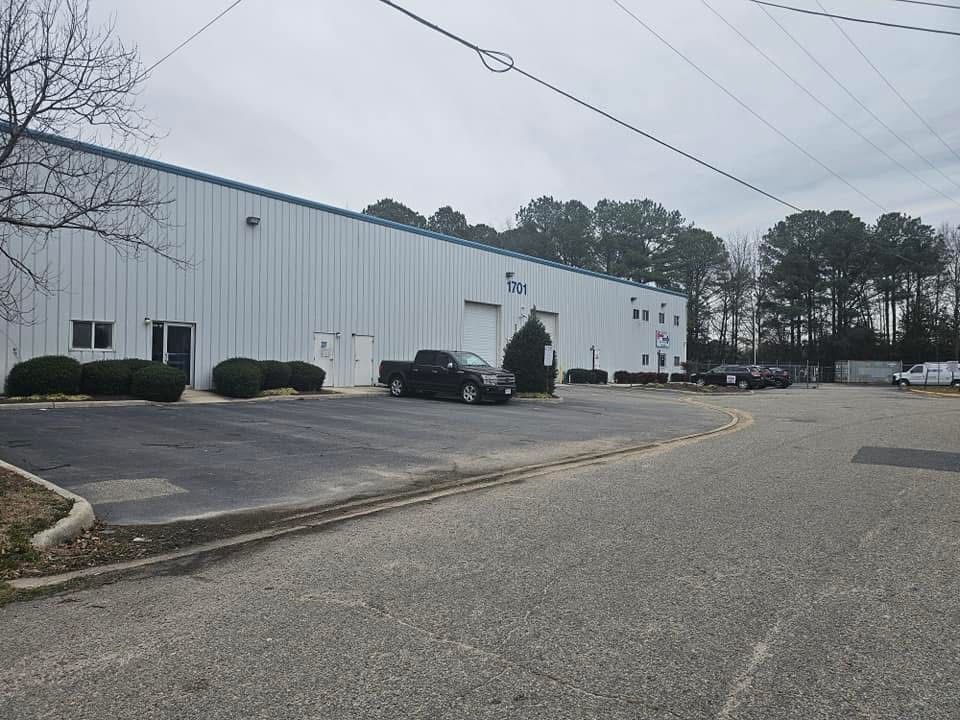 White industrial building beside an empty parking lot on an overcast day