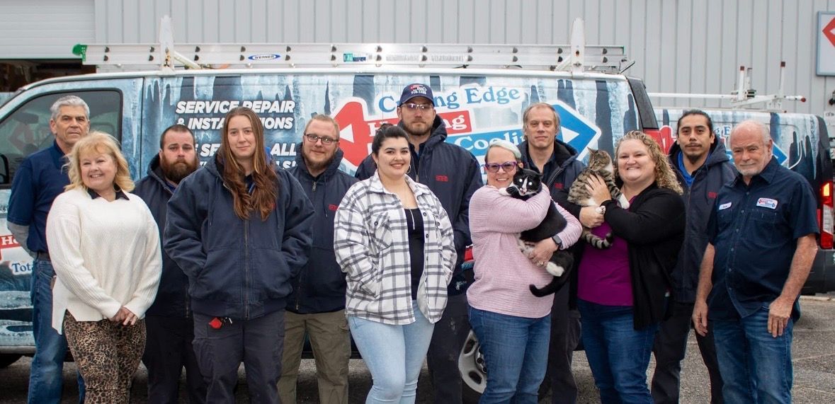 Group of people standing together outside a white van, posing and smiling in casual jackets and sweaters.