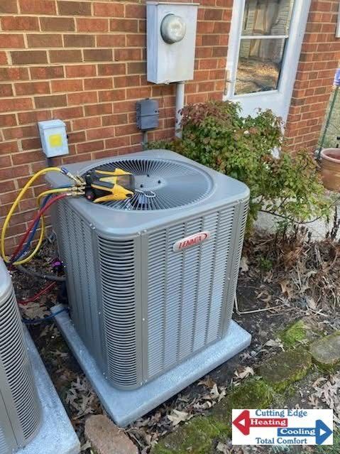 Outdoor HVAC condenser unit beside a brick house with service gauges and lines attached
