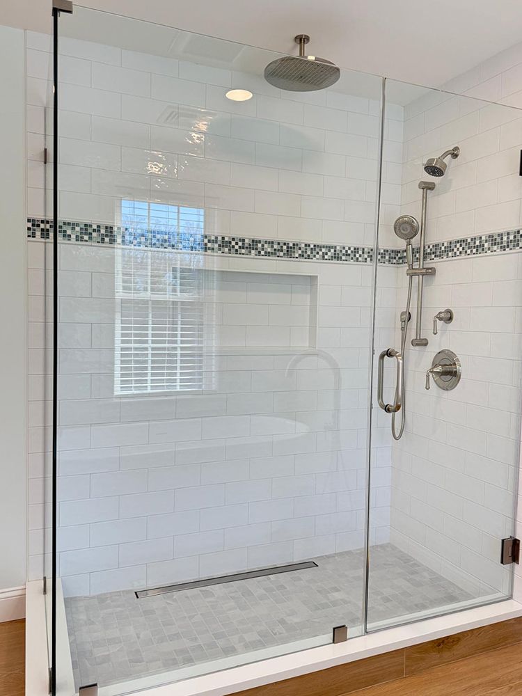 Glass shower enclosure with white subway tile, a rain showerhead, and a built-in soaking tub.