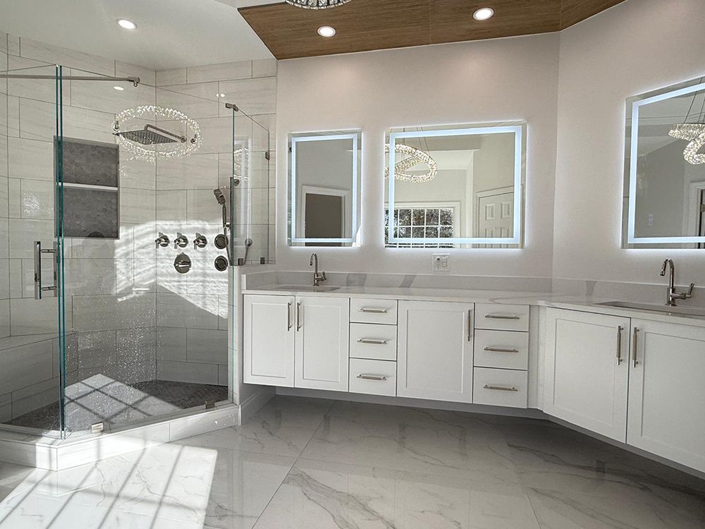Modern white bathroom with glass shower, double sinks, and bright LED mirrors.