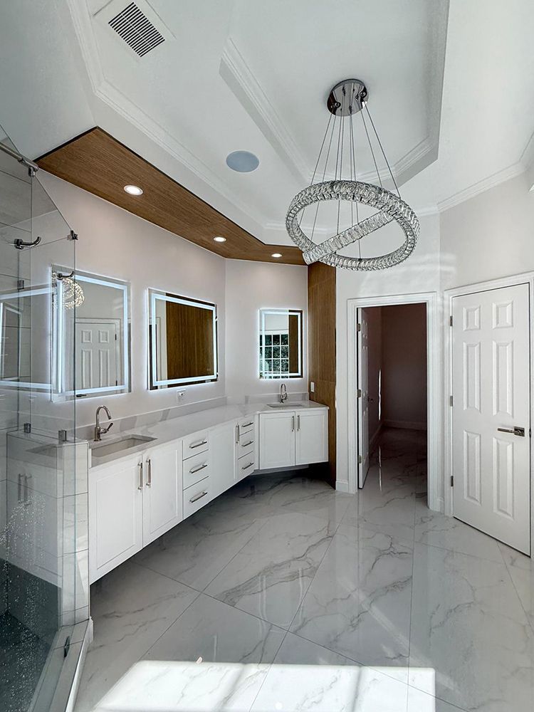 Spacious white bathroom with double vanity, marble floors, and a modern chandelier.