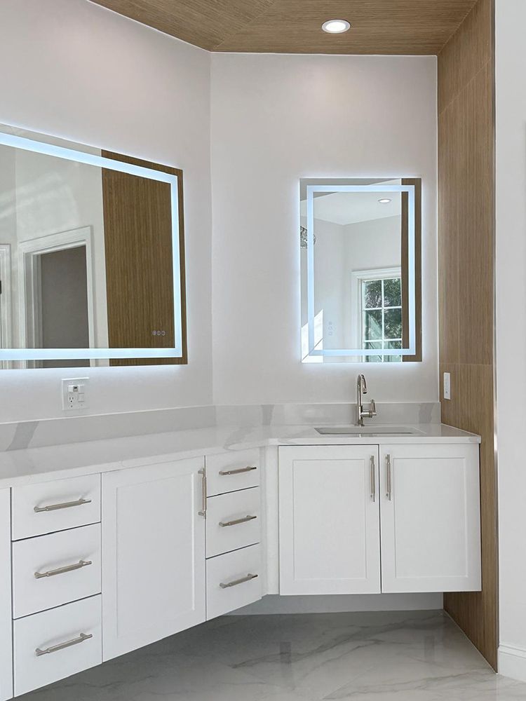 Modern white bathroom with floating vanity, LED mirrors, and marble countertop.