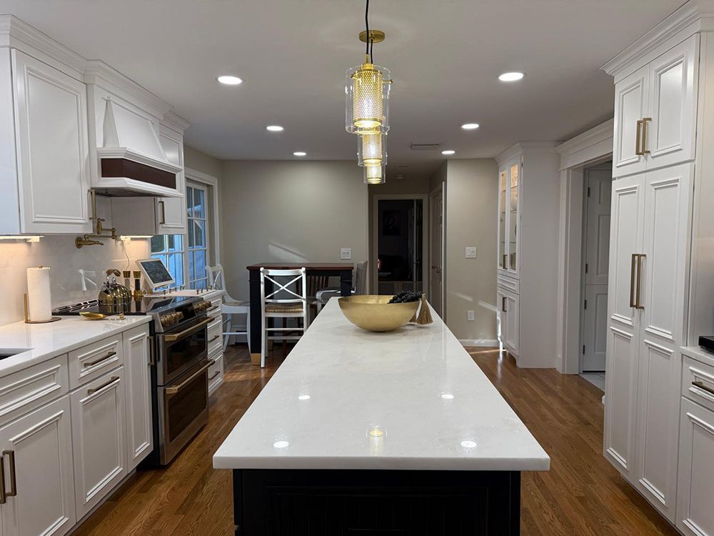 Bright, modern kitchen with white cabinets, a large island, and a gold light fixture.