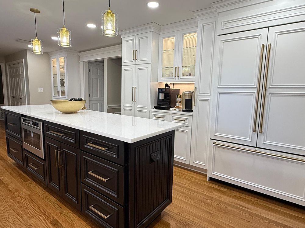 Elegant kitchen with white cabinetry, black island, and gold accents.