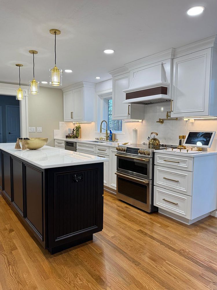Modern kitchen with black island, white cabinets, and stainless steel appliances.