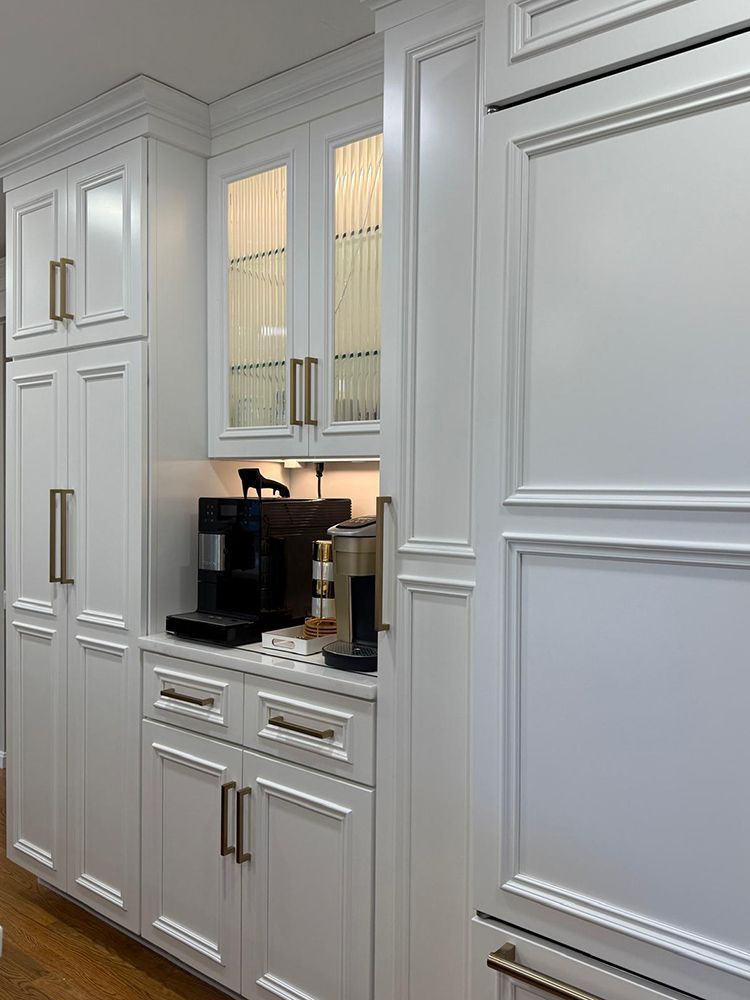 White kitchen cabinets with gold hardware and integrated coffee machines.