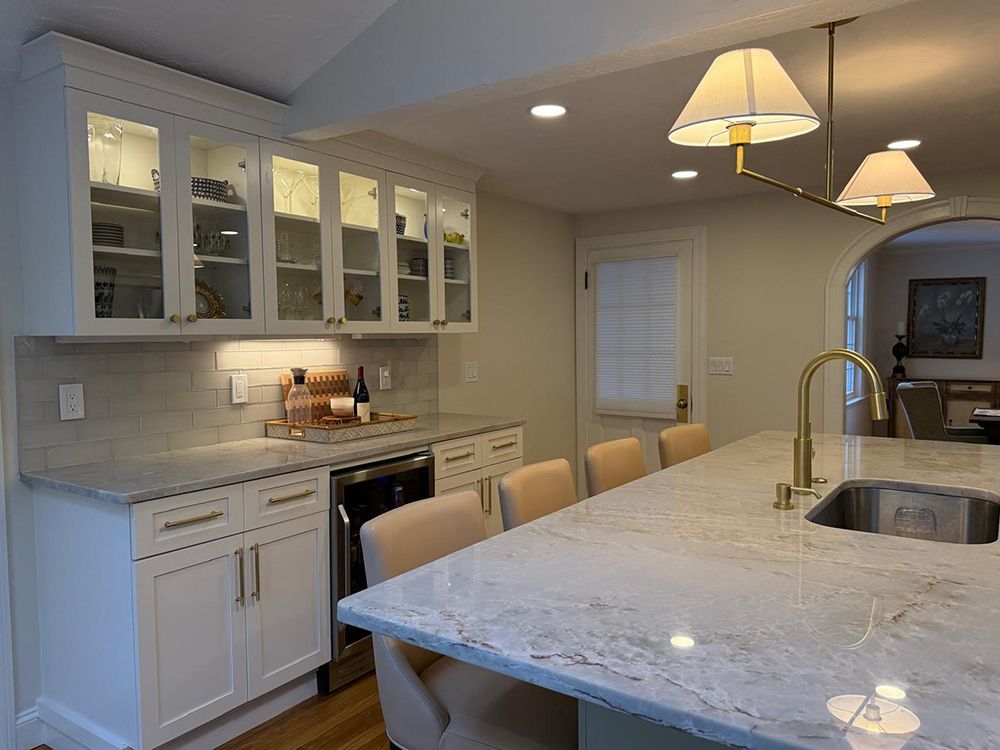 Kitchen with white cabinets, a large island, and gold fixtures; light beige walls.