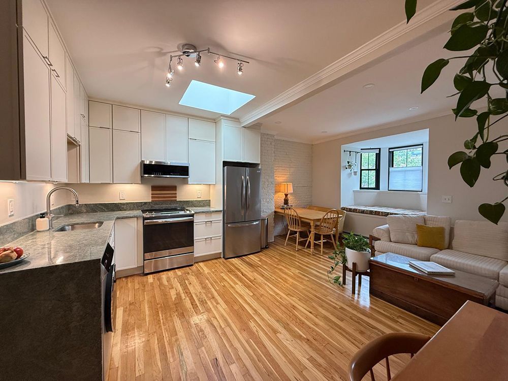Kitchen with light wood floors, white cabinets, stainless steel appliances, and a seating area.