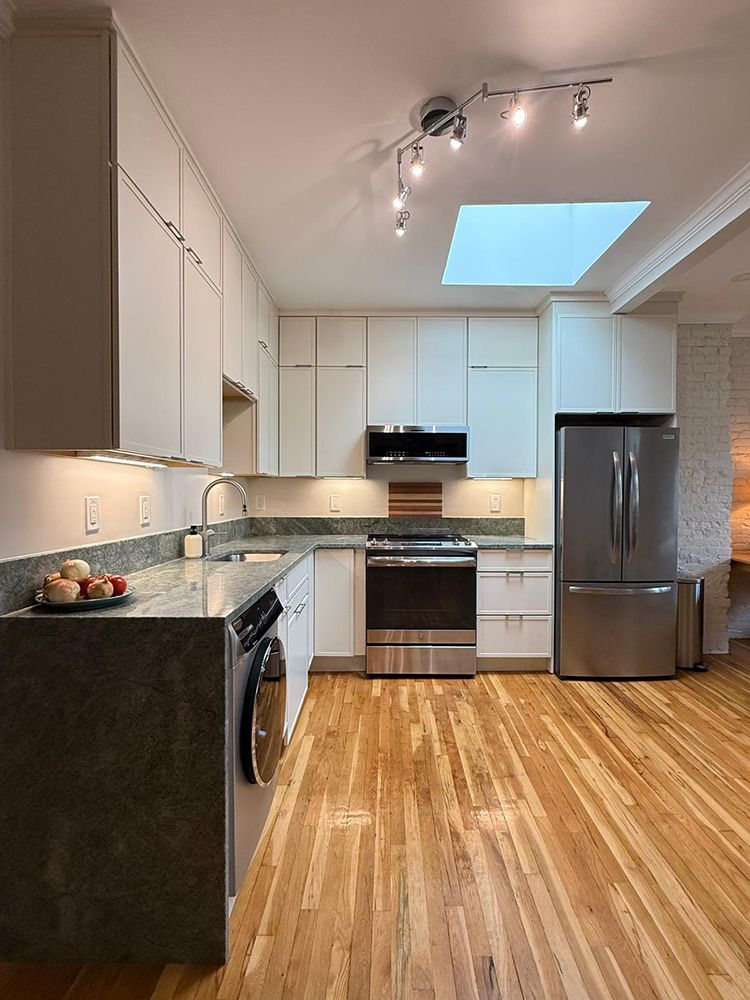 Modern kitchen with white cabinets, stainless steel appliances, granite countertops, and hardwood floors.