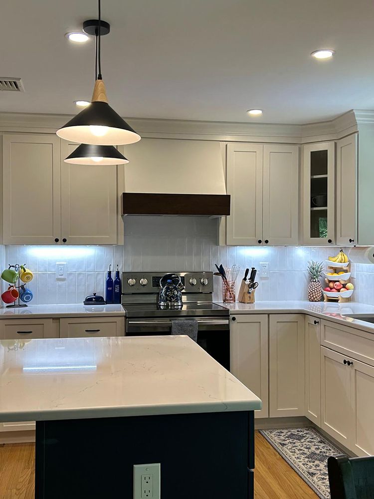 Modern kitchen with white cabinets, stainless steel appliances, and a dark blue island.