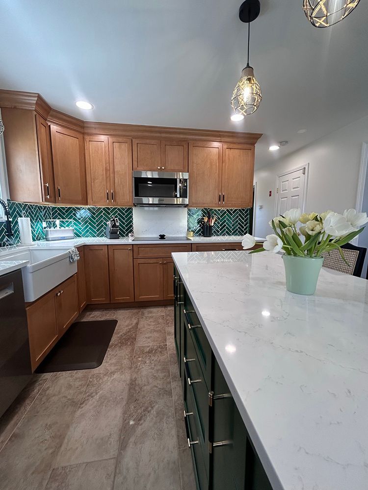 Kitchen with light wood cabinets, a green backsplash, and a green island with white countertop.