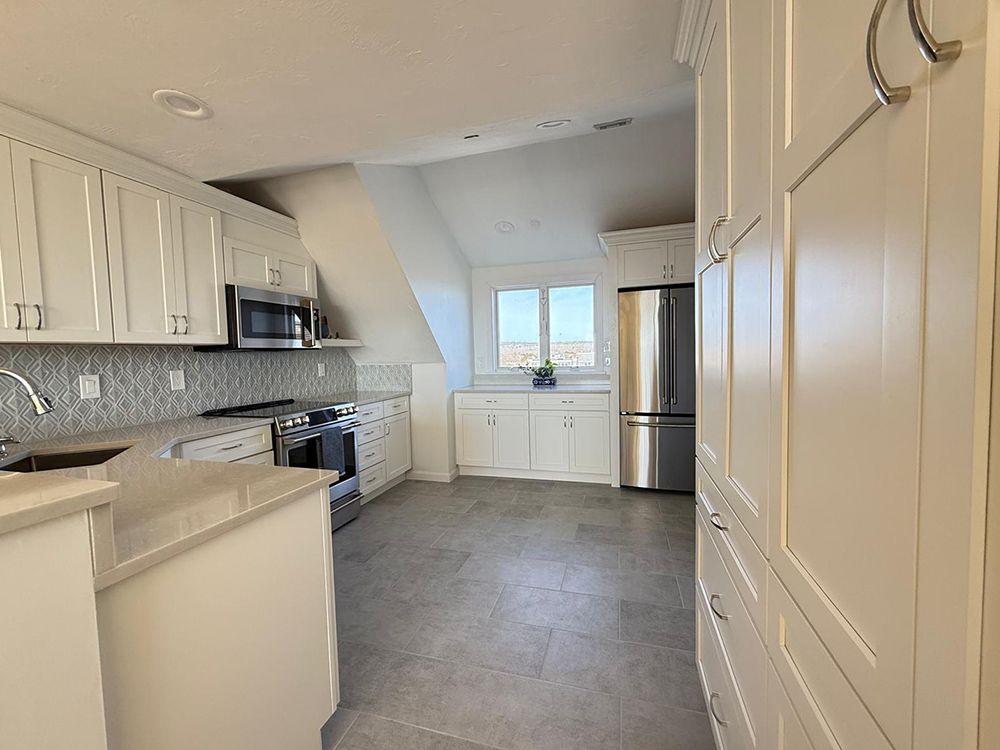 White kitchen with stainless steel appliances and gray tile flooring.