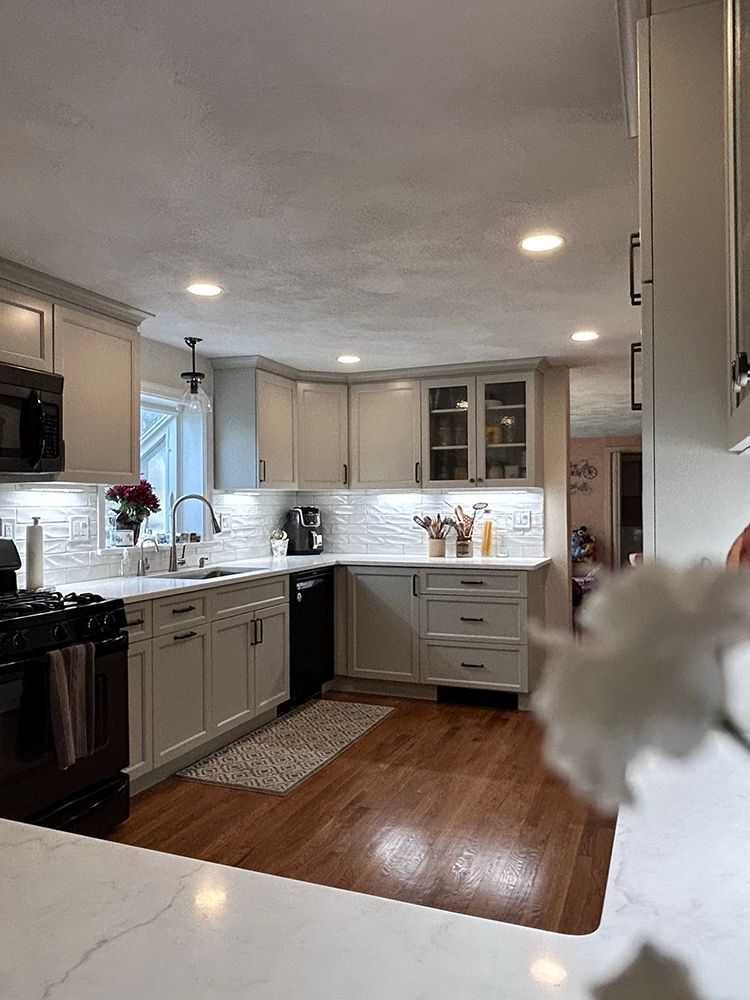 Newly renovated kitchen with gray cabinets, white countertops, and hardwood floors.