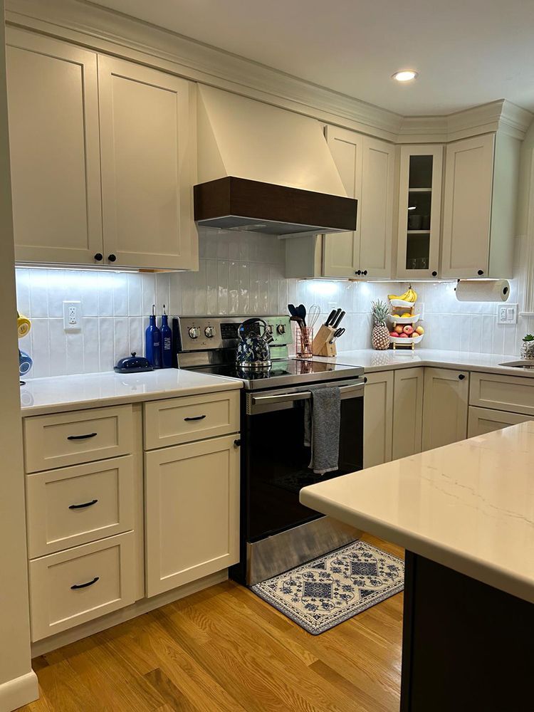 Cream-colored kitchen with white countertops, stainless steel appliances, and a dark brown range hood.