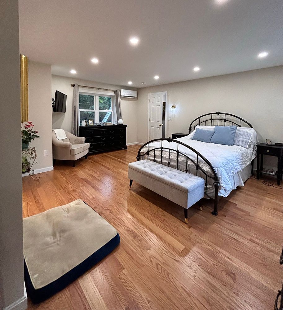 Spacious bedroom with hardwood floors, a bed, and a dog bed on the floor.