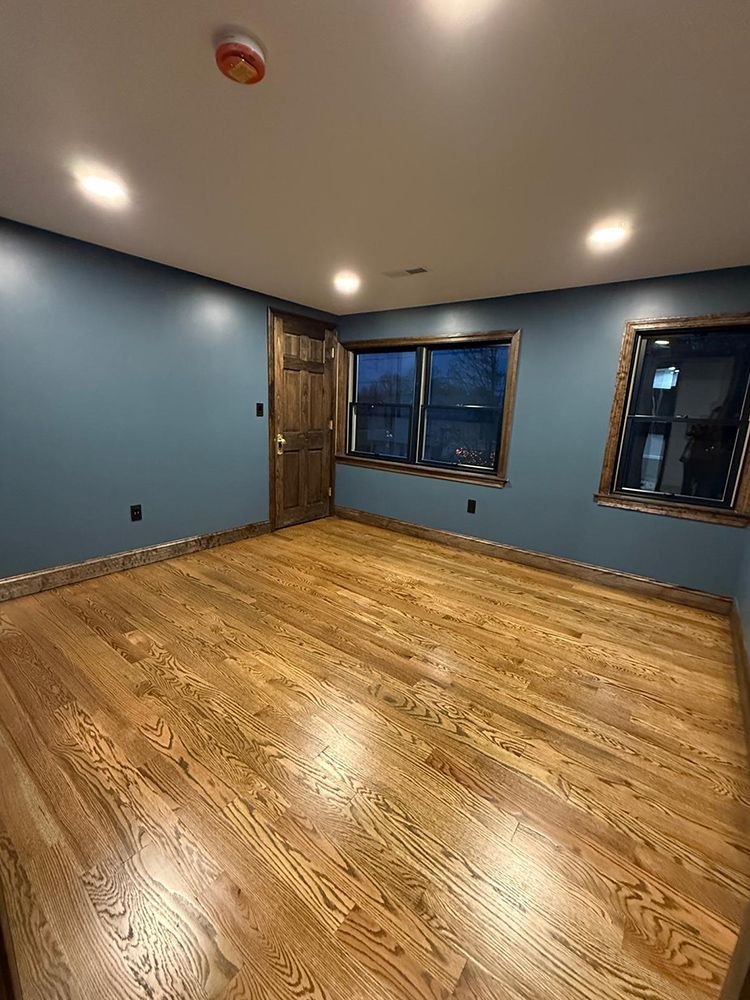 Empty room with wood floors, blue walls, and wooden door and window frames.